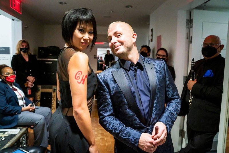 Yuja Wang and Yannick Nézet-Séguin pose for a photo backstage at Carnegie Hall. On Yuja's bare shoulder is a version of the CH monogram hand-drawn with lipstick.