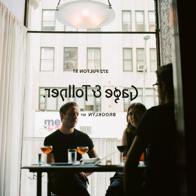 People eating at a table in front of a window with the Gage & Tollner logo