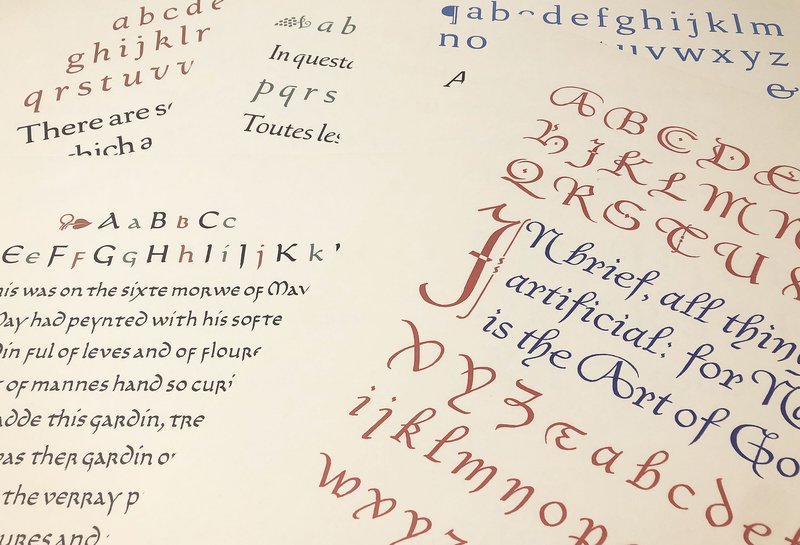 Several artistic prints of lettering samples are stacked
