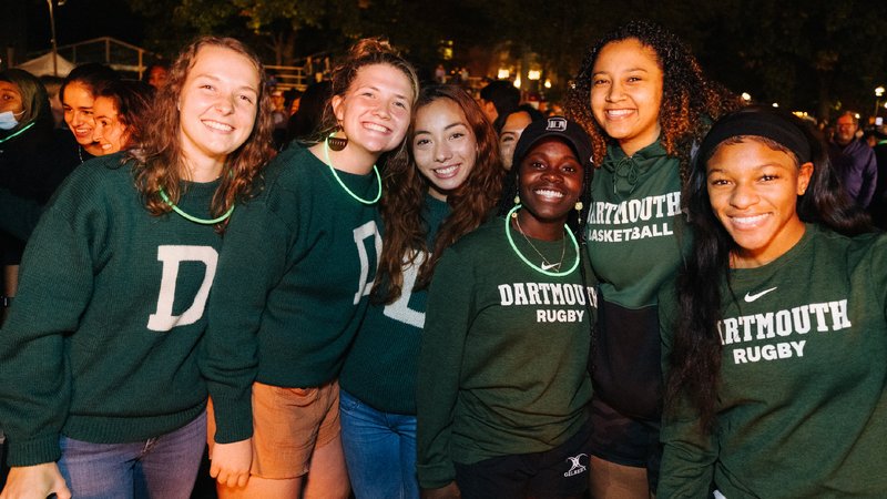 A group of people wear green sweatshirts with the Dartmouth Athletics logo