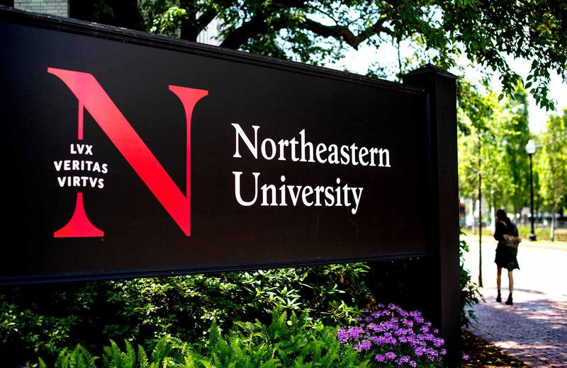 A black sign features the N monogram with motto, locked up with the Northeastern University logotype